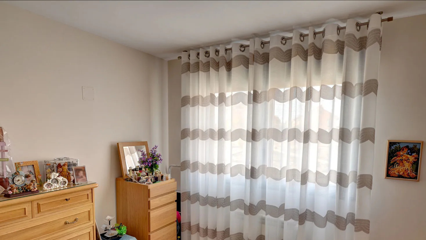 Dormitorio con una cortina de ollaos colgada de una barra plateada