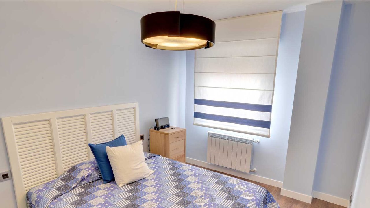 Estor de varillas blanco con franjas azules en un dormitorio