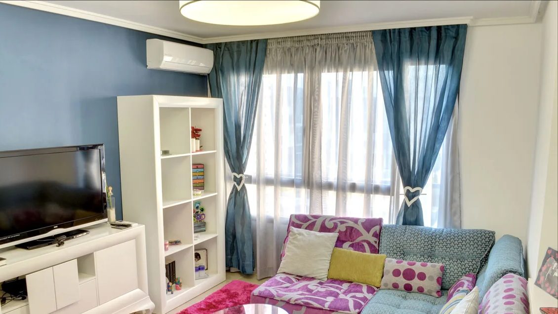 Salón con visillos lisos de color azul, recogidos a los lados con alzapaños