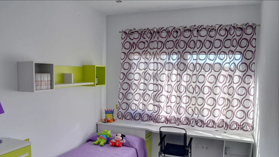 Habitación juvenil con una cortina de ollaos de espirales en berenjena sobre blanco