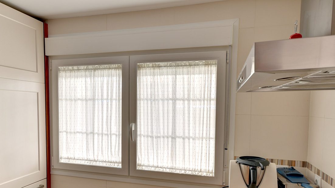 Cocina con un visillo de gusanillo en cada hoja de la ventana, dentro del marco