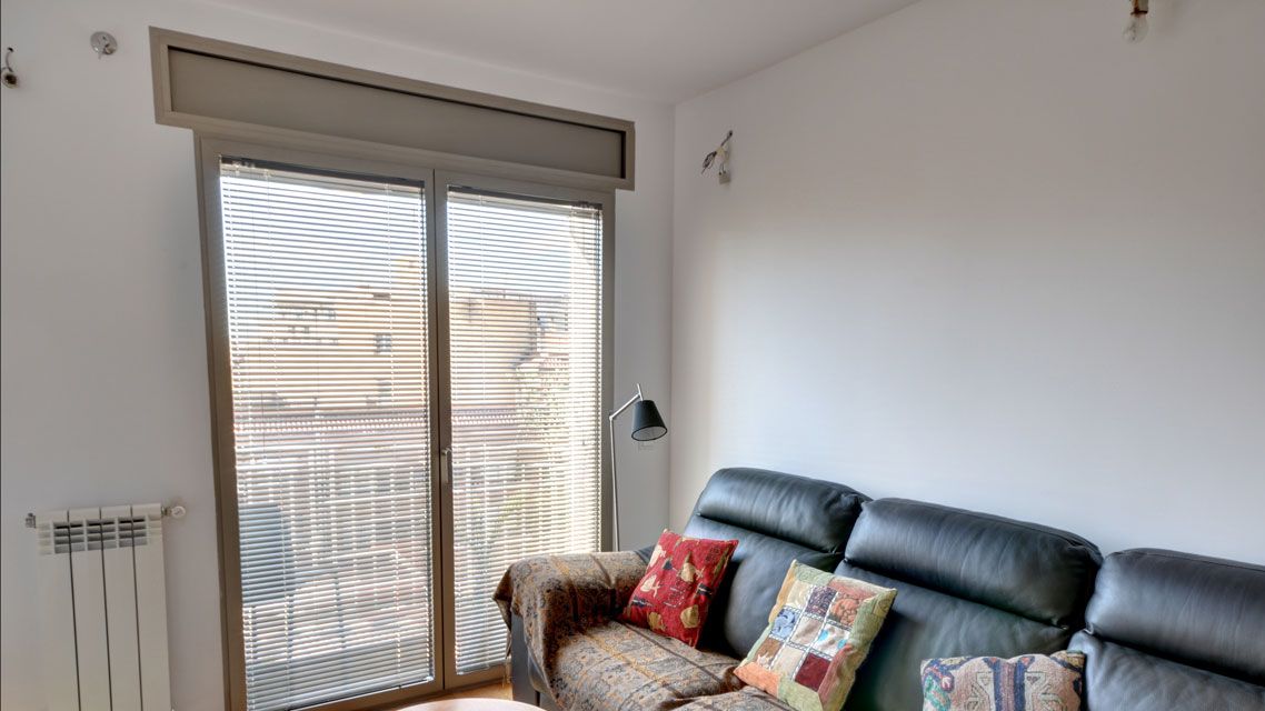 Salón con persiana veneciana de aluminio en la puerta de la terraza