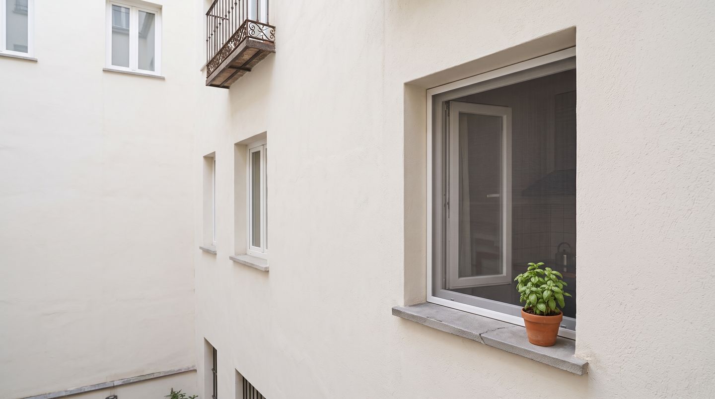 Ventana pequeña vista desde fuera con una mosquitera fija de marco de aluminio en el hueco