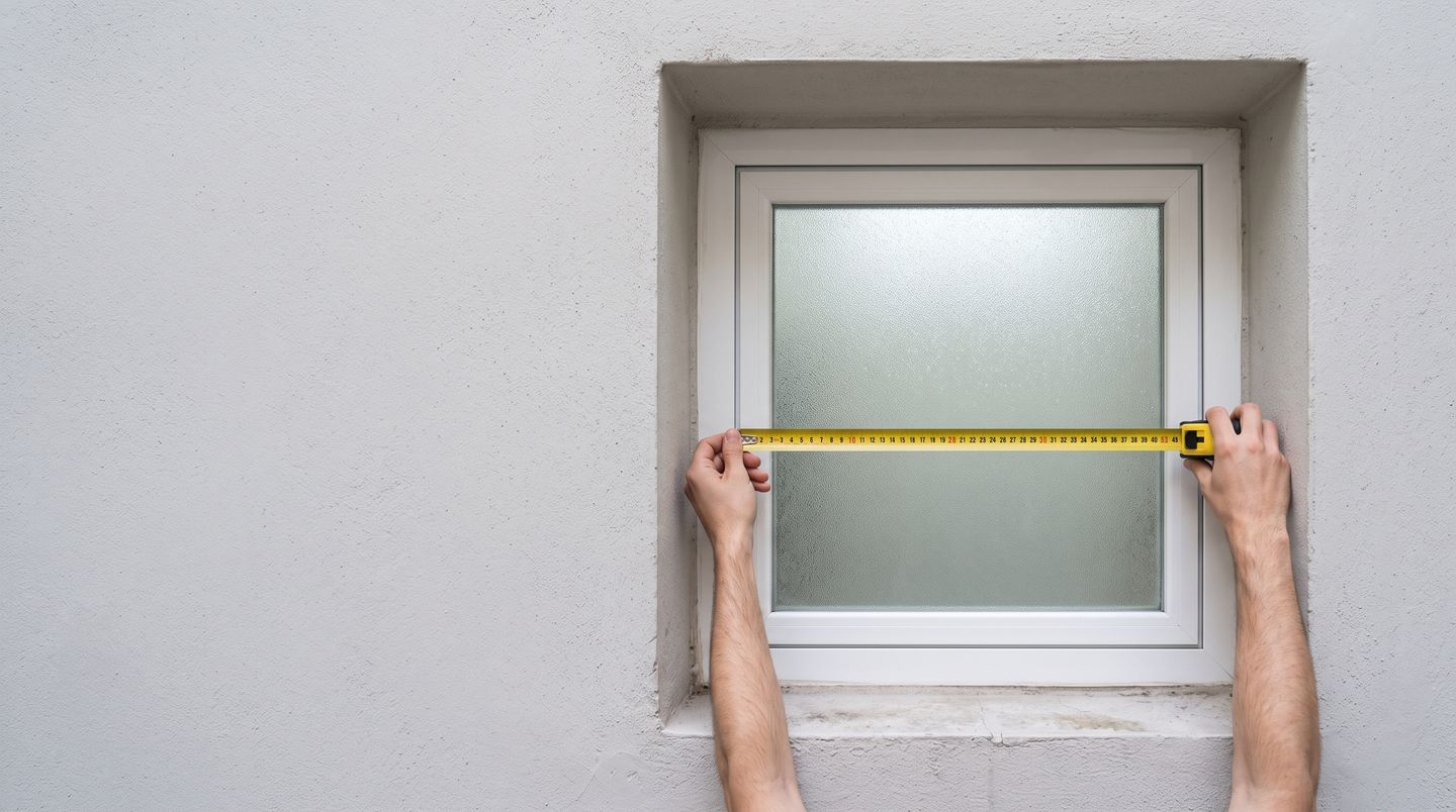 Midiendo con un metro el ancho de una ventana pequeña de baño, por dentro del marco