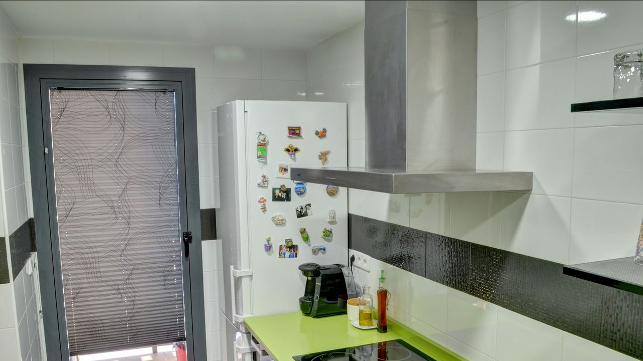 Cocina con persiana plisada en la puerta de la terraza