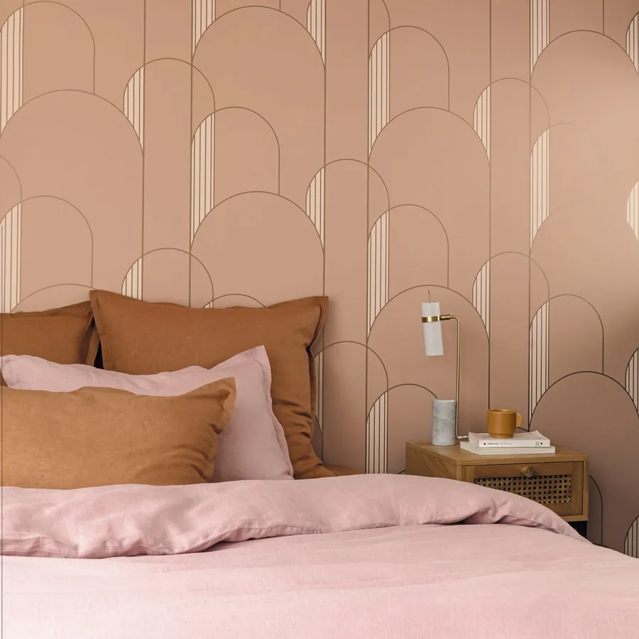 Dormitorio con papel pintado de arcos en tono rosa detrás de la cama