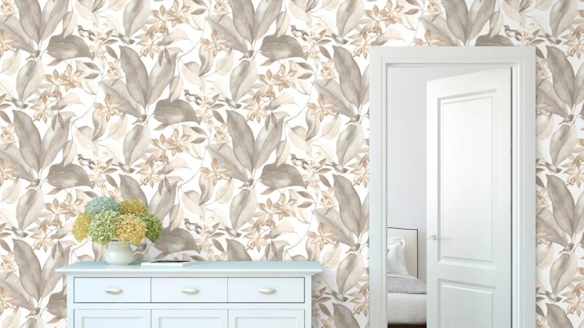 Pared con papel pintado de hojas y flores en tonos suaves junto a una cómoda blanca