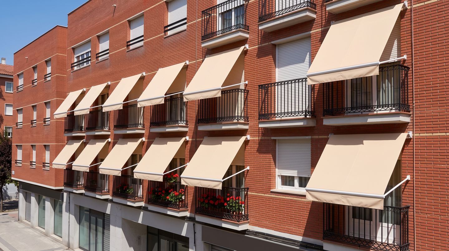 Fachada de ladrillo de un edificio de Madrid con toldos de punto recto iguales en todos los balcones