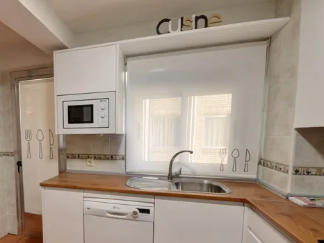 Cocina blanca con estor enrollable en la ventana