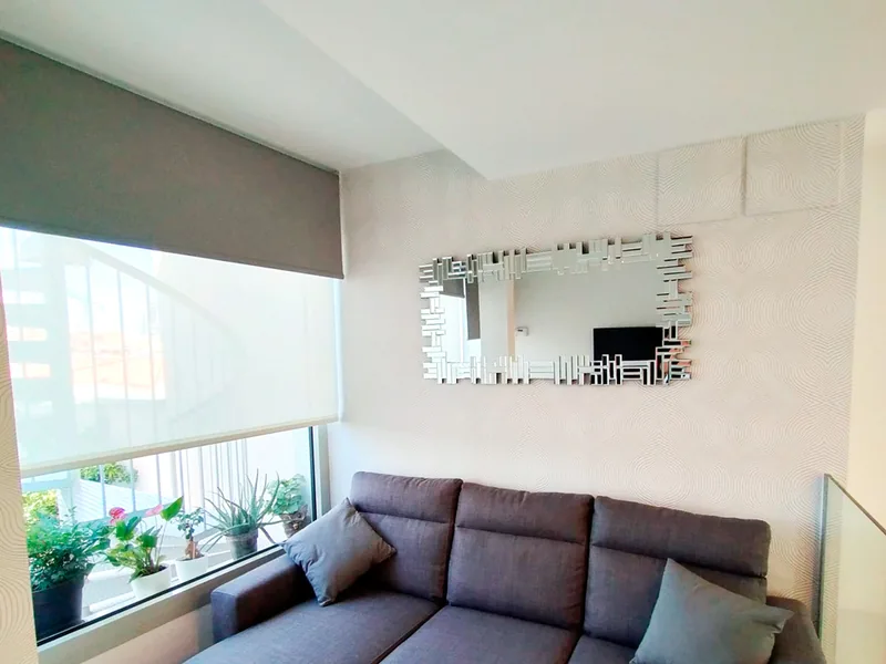 Salón con papel pintado, espejo y estor enrollable doble