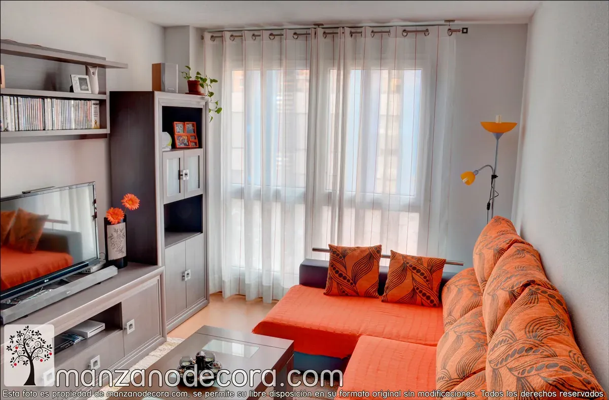 Detalle de barra para cortinas con ollaos y cortina que cae por delante de la ventana en un salón